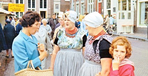 Markt op de grote markt, twee vrouwen in streekdracht praten met een andere vrouw