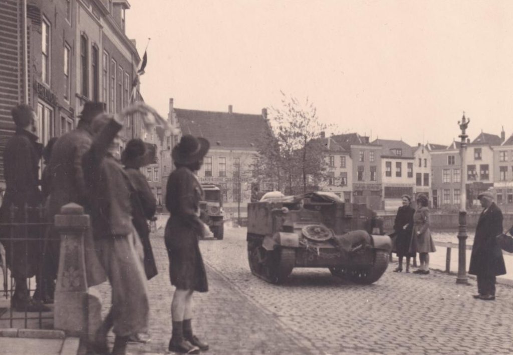 Mensen staan langs de kade tijdens de bevrijding, er komt een tank voorbij