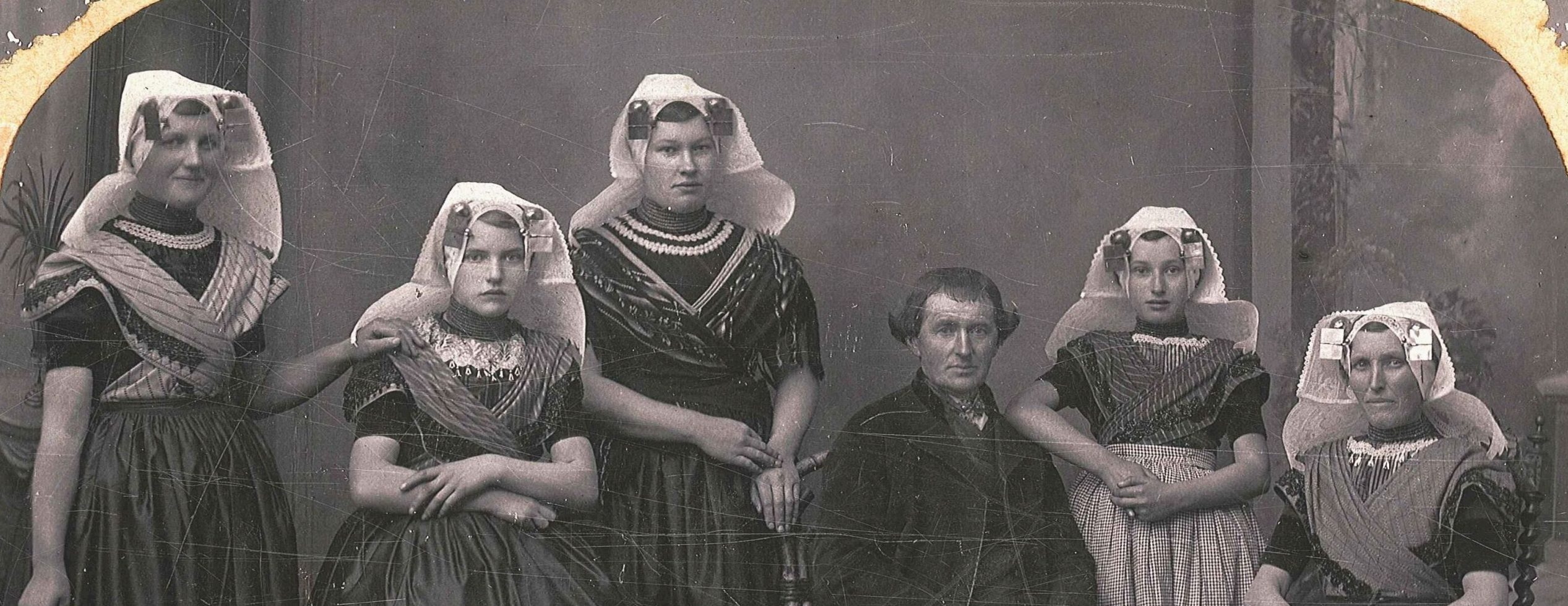 Portret van man in Zuid-Bevelandse dracht zonder hoed, vrouw en vier jonge vrouwen in Zuid-Bevelandse dracht.