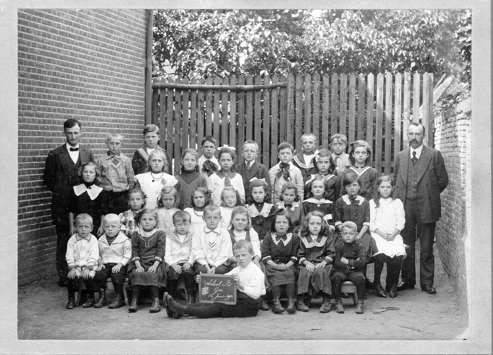 Klassenfoto met jonge kinderen, links en rechts staan hun onderwijzers