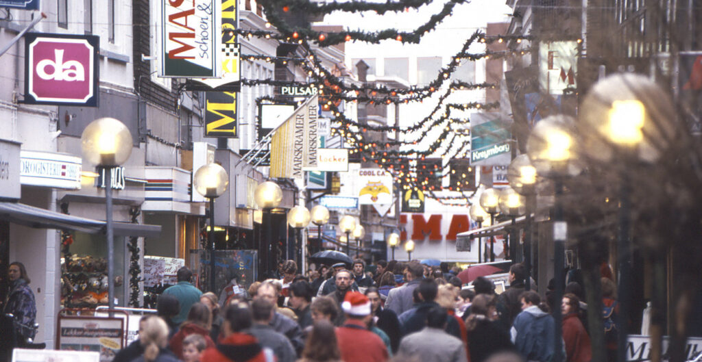 Volle winkelstraat. Kerstversieringen hangen op.