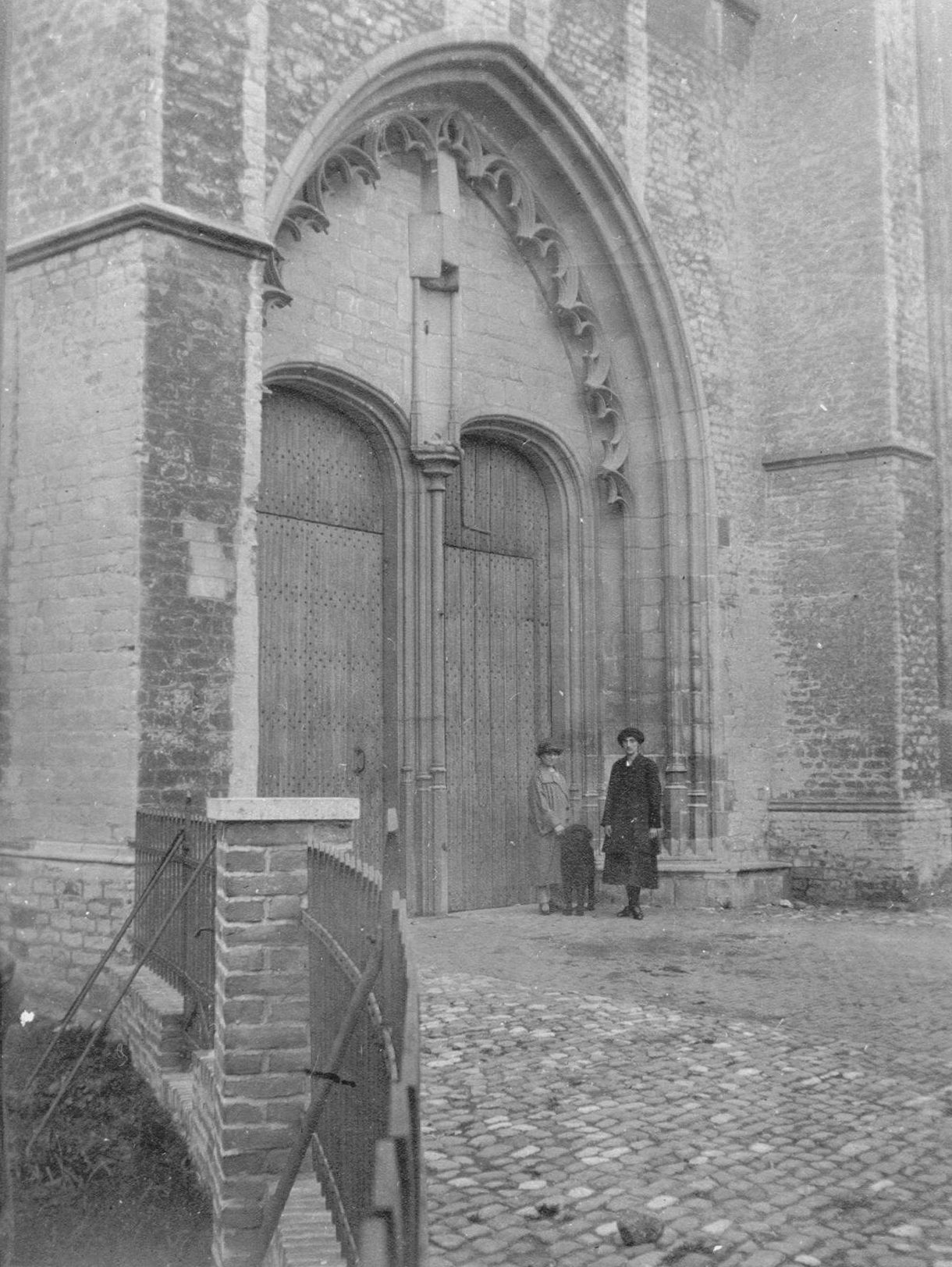 Zuidtransept buitenkant. Twee mannen staan voor de deur. 