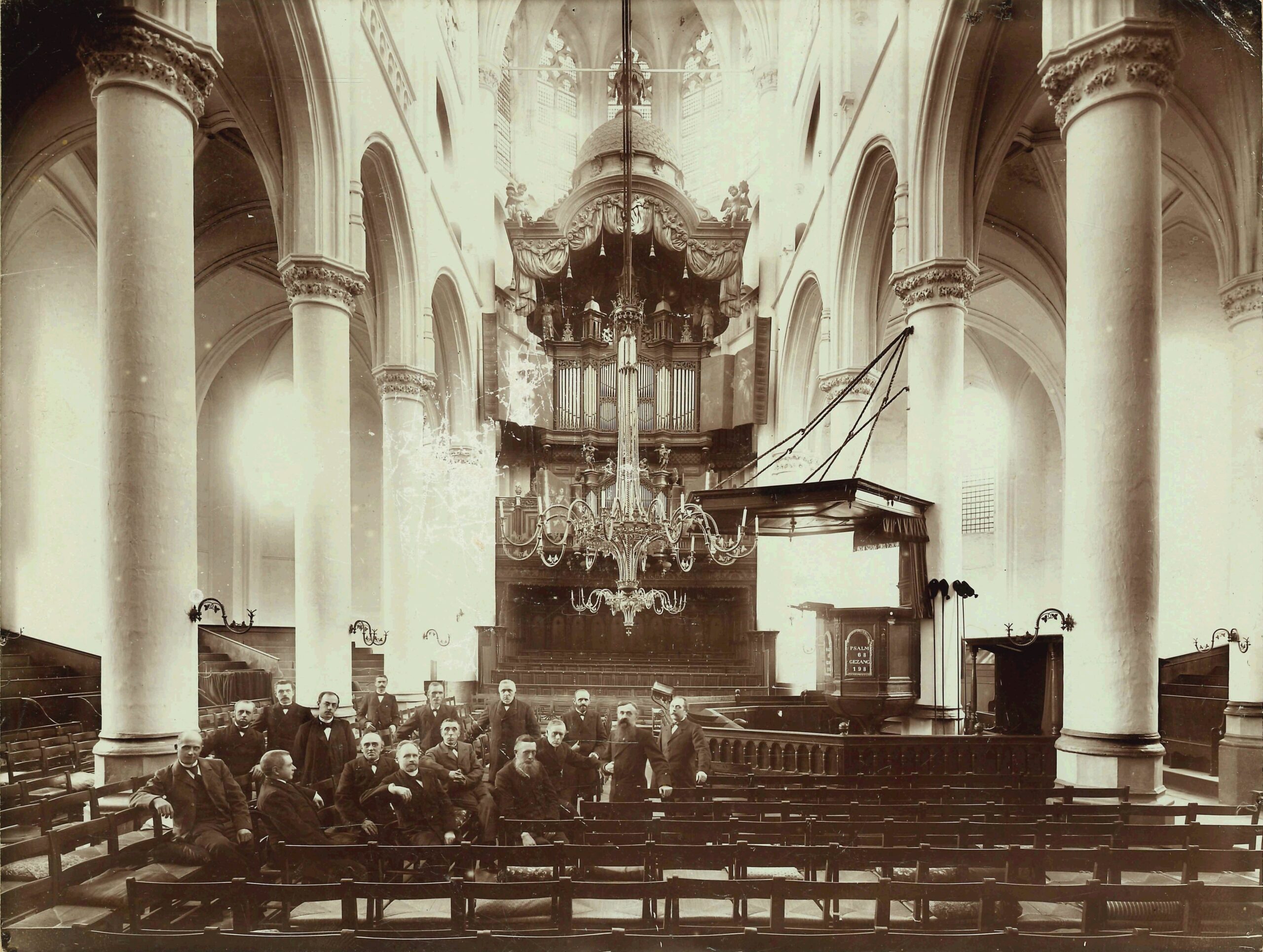 Koor met een groep mannen links, rechts de preekstoel en achterin het orgel.